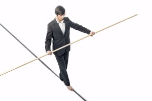 Businessman walking a tightrope - isolated on white